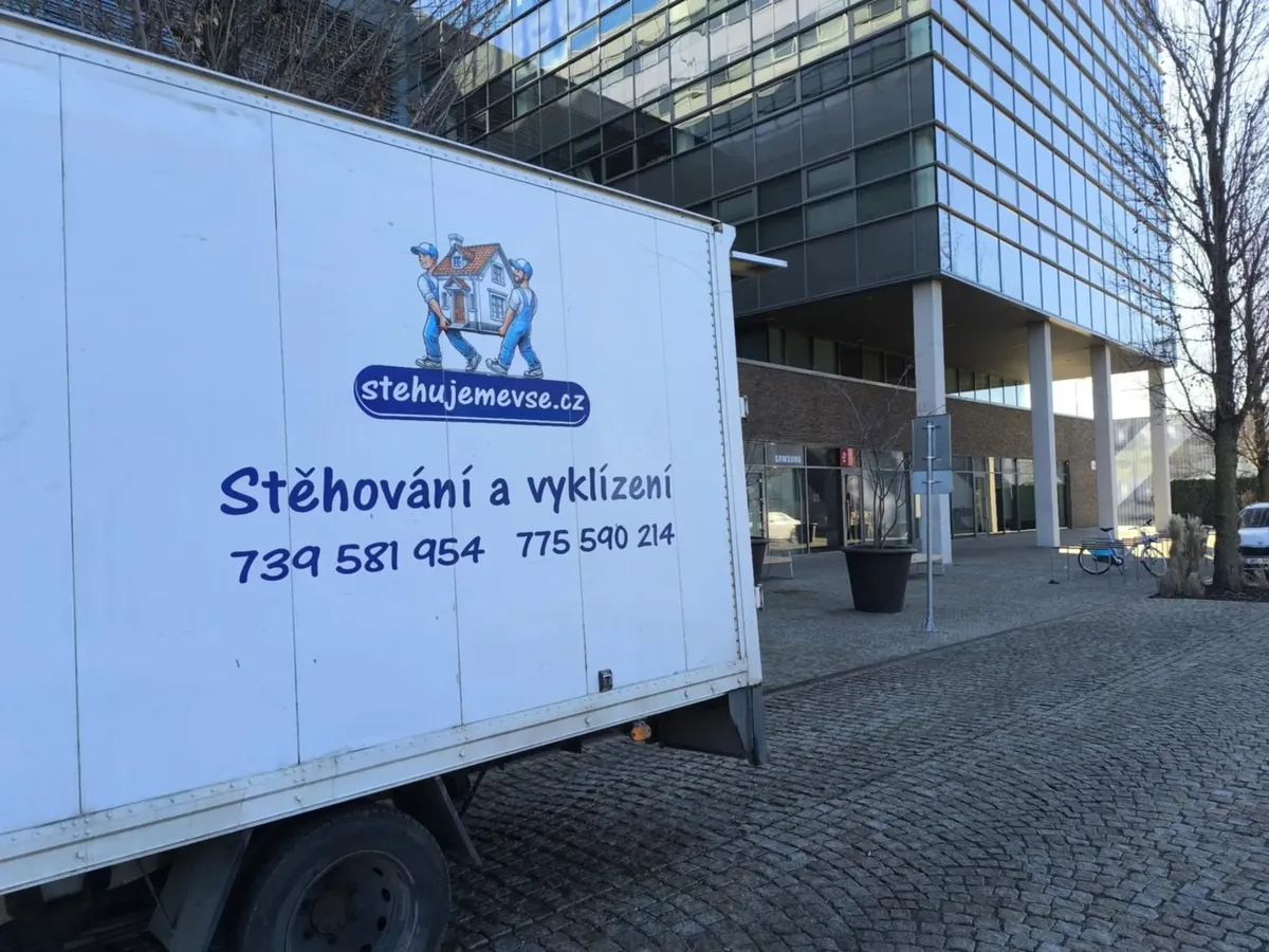 Stěhovací vůz firmy Stěhujeme Vše s logem před budovou v Brně